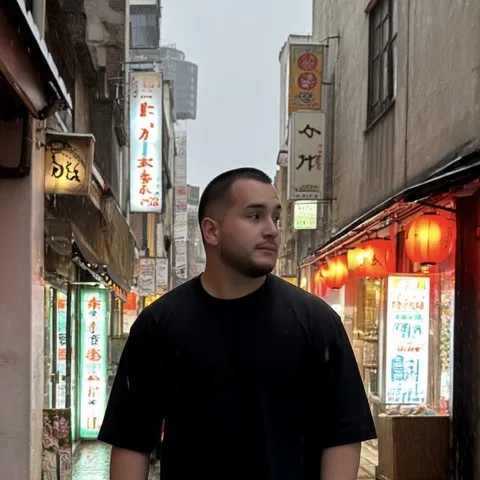 Enrique numa viela japonesa à noite, camiseta preta larga, lanternas vermelhas e letreiros acesos atrás.